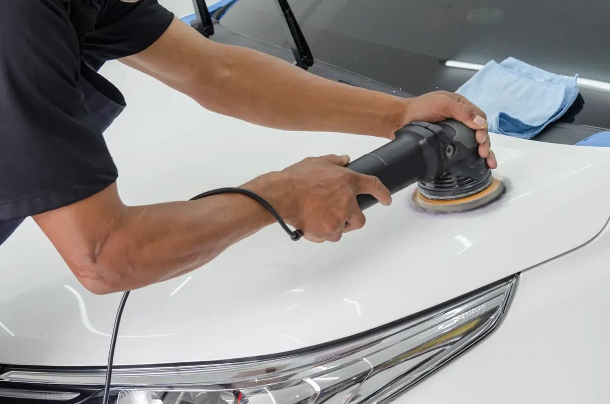 Een motorkap wordt met een polijstmachine gepolijst